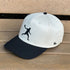 White cap with black visor and black silhouette of a person on a wooden surface